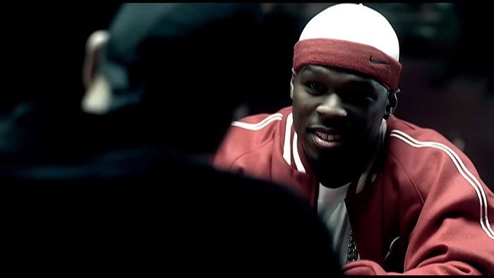 Man in red jacket and headband raps in a dark setting representing hard rock cover of 50 Cent's Many Men viral song.