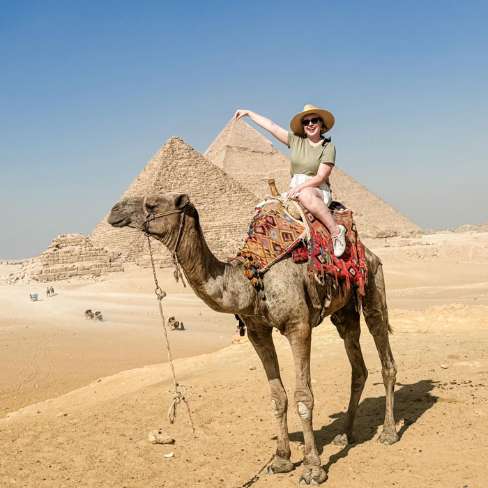 Woman riding a camel near pyramids in the desert, symbolic image for pregnant Disney superfan found lifeless news.