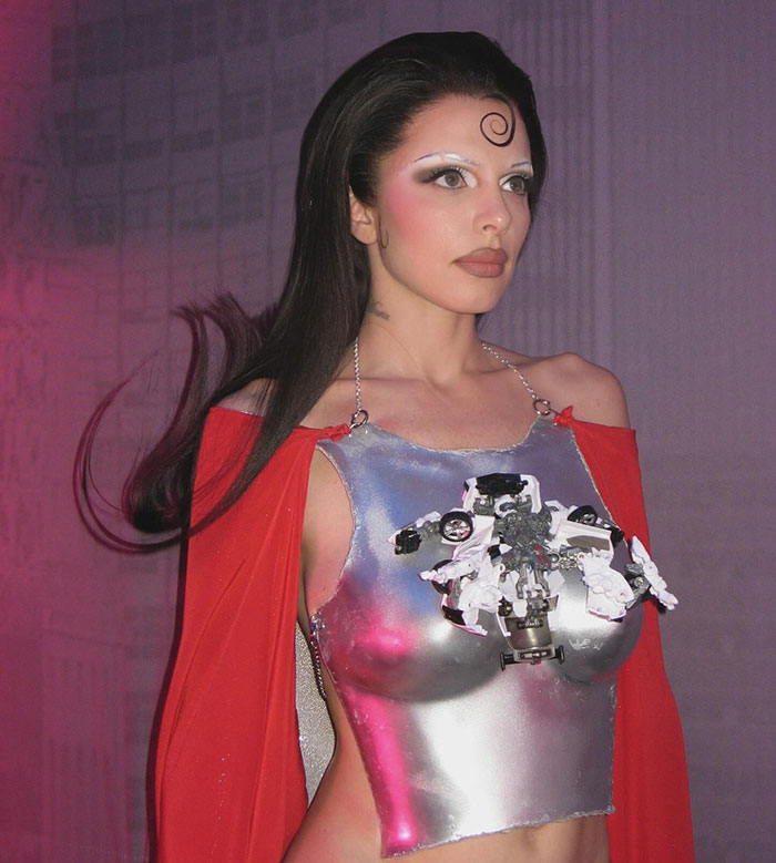 Julia Fox wearing a metallic barely-there dress with sculptural details and a red cape at a gala event.