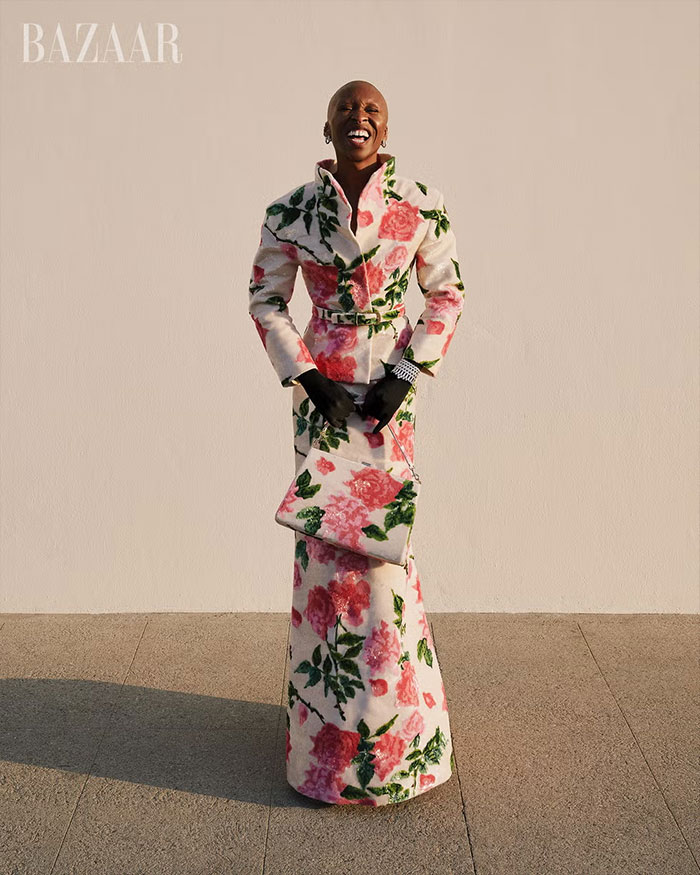 Cynthia Erivo in floral patterned coat dress and matching bag posing for controversial Harper&rsquo;s Bazaar shoot outdoors.