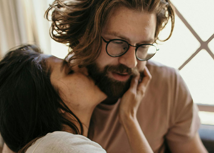 Woman whispering closely to a man wearing glasses, capturing a moment related to creepy things women said or did to men.