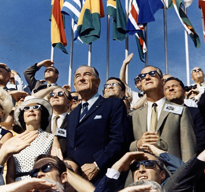 Group of people wearing sunglasses and looking up, representing public reaction to Kim Kardashian's moon landing conspiracy rant.