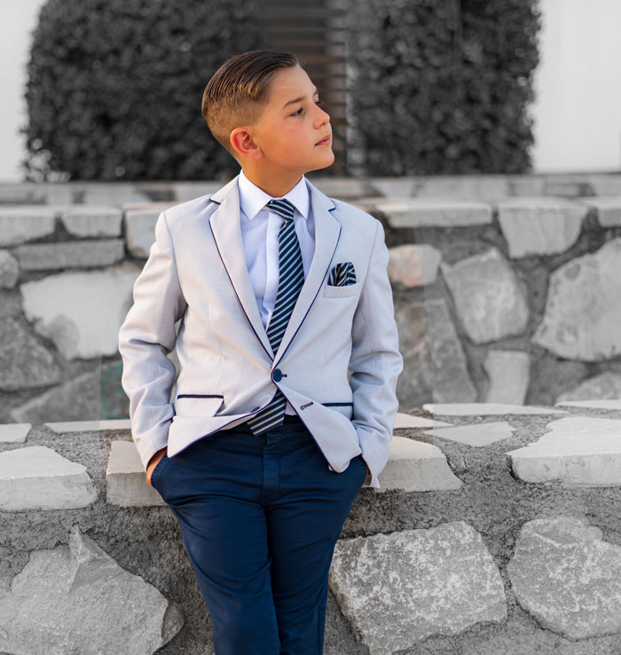 Young boy in a suit standing confidently outdoors symbolizing strength after enduring narcissistic mothers' challenges.