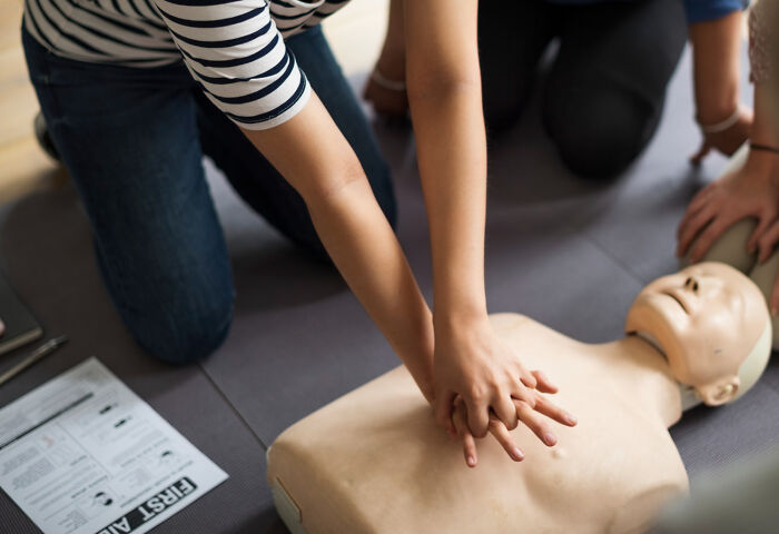Person performing CPR on a training mannequin with others nearby, illustrating health hacks shared by doctors and nurses.