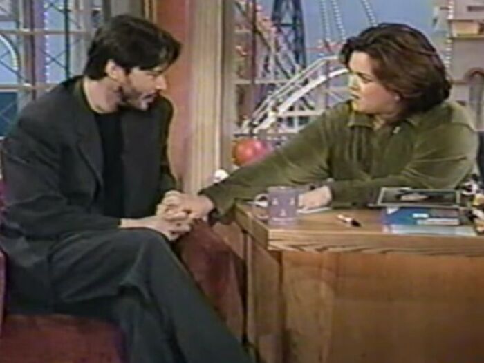 Rosie O'Donnell interviewing Keanu Reeves on a talk show set, capturing a tense and serious moment between them.