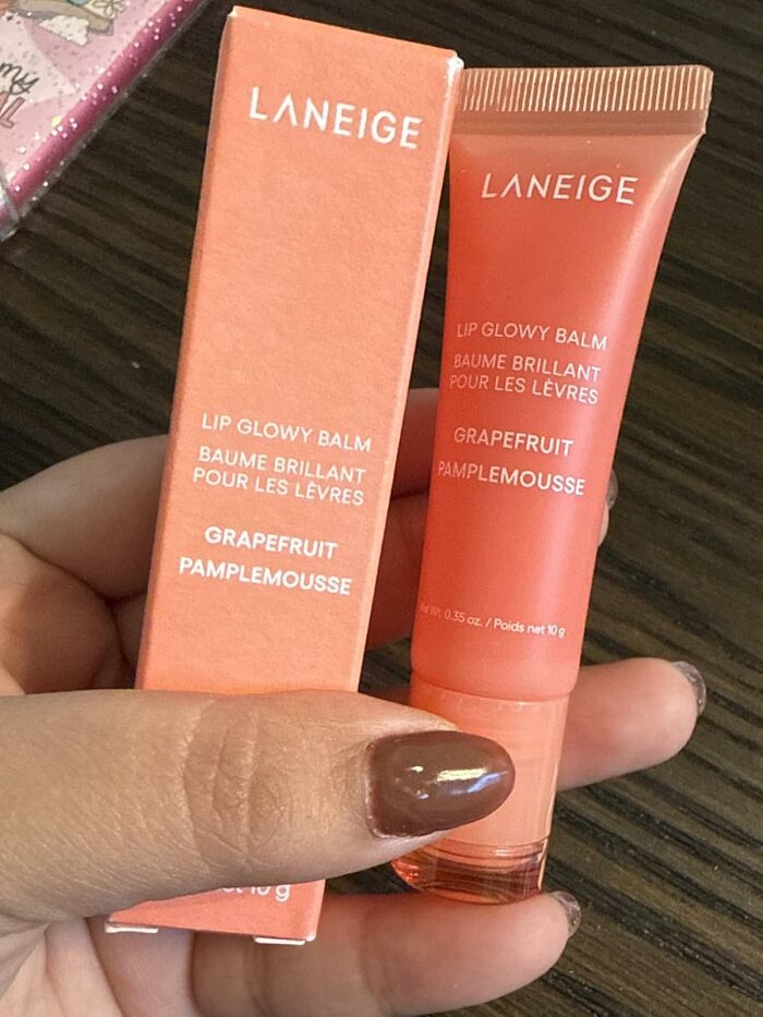 Hand holding Laneige Lip Glowy Balm grapefruit flavor, one of the viral products from Amazon's Big Deal Days.