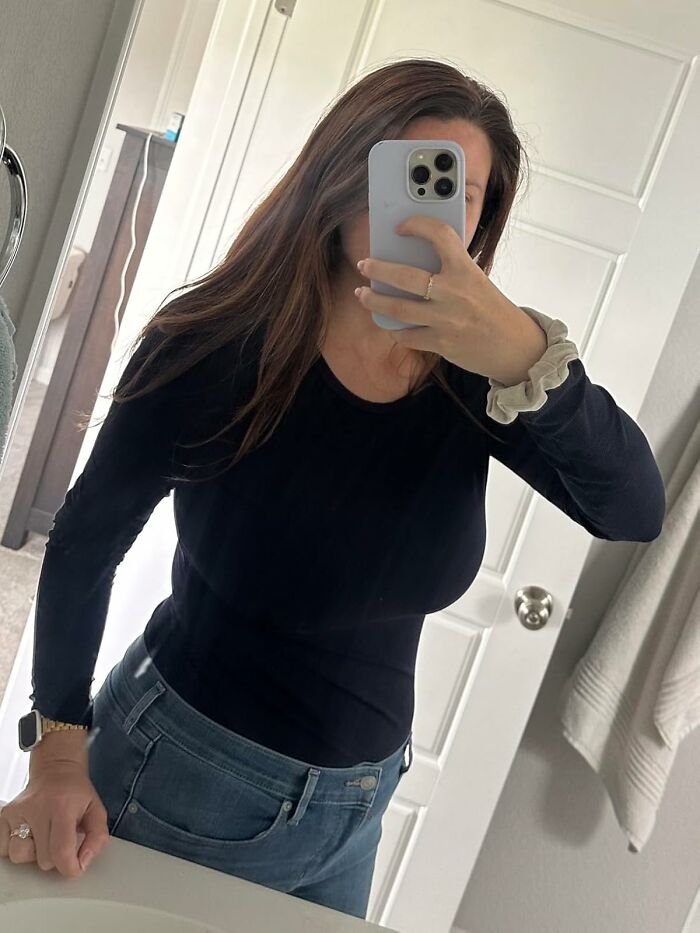 Woman wearing black long sleeve shirt and jeans taking a mirror selfie showcasing viral products bought during Amazon's big deal days.