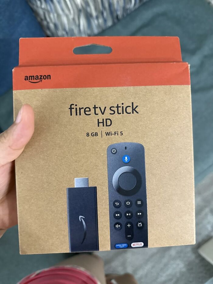 Amazon Fire TV Stick HD packaging held by hand showing viral products bought during Amazon deal days.