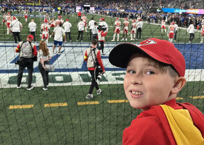 Young boy in a red cap at a football stadium amid Kansas City Karen viral incident surrounding a headband dispute.