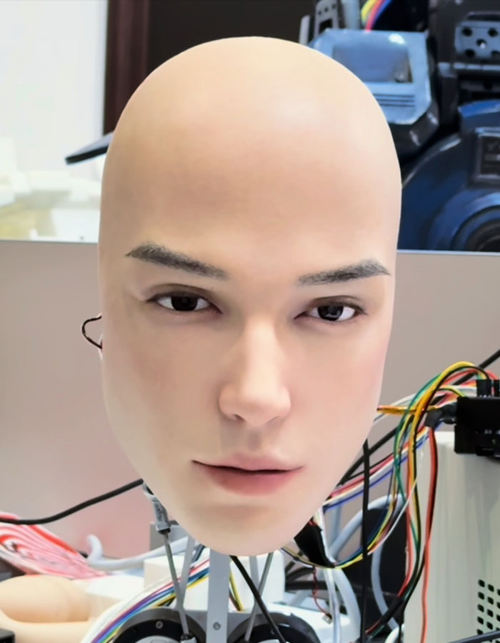 Realistic robot head with human-like face and electronic wires, sparking debate about technology going too far.