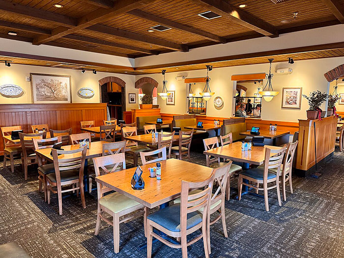 Cozy Italian restaurant interior with wooden tables and chairs, highlighting American tourist dining experience in Italy.