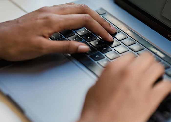Hands typing on a laptop keyboard illustrating life hacks people discovered accidentally and still use today.
