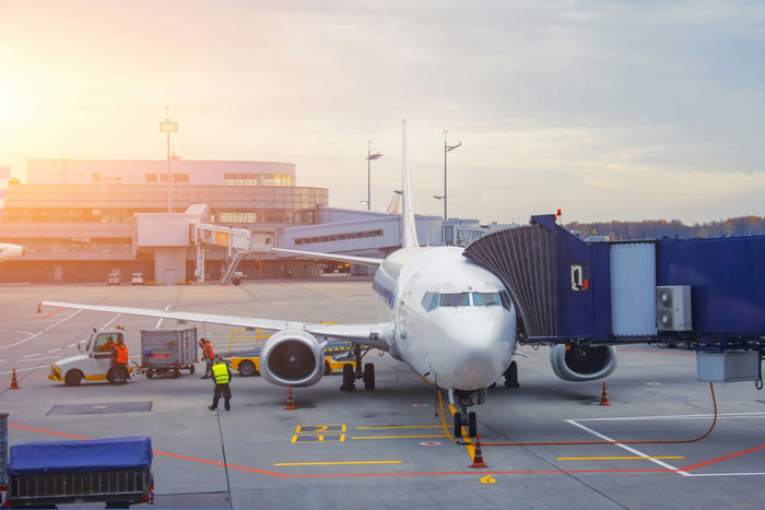 Passenger jet at the gate with ground crew working, illustrating a scene related to Karen locking horns with passengers on plane. Passenger jet at the gate with ground crew working, illustrating a scene related to Karen locking horns with passengers on plane.