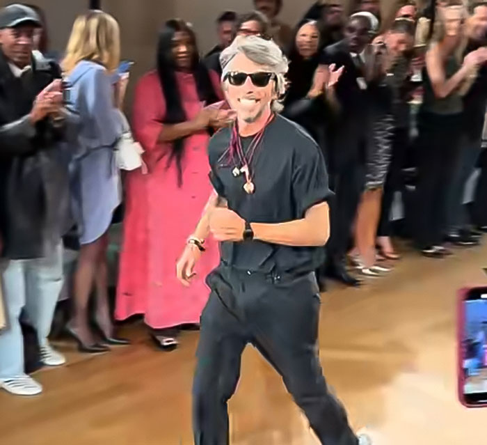 Balenciaga designer walking on runway at Paris Fashion Week with audience clapping and taking photos in the background