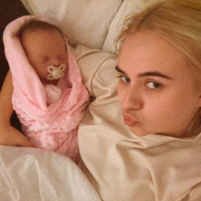 Young woman lying on bed holding a baby doll wrapped in a pink blanket, highlighting an outrageous 10-month lie.