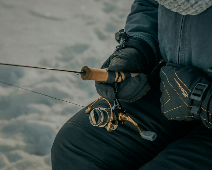 Close-up of gloved hands holding a fishing rod, illustrating a quiet moment amid discussions of worst crimes in hometowns.