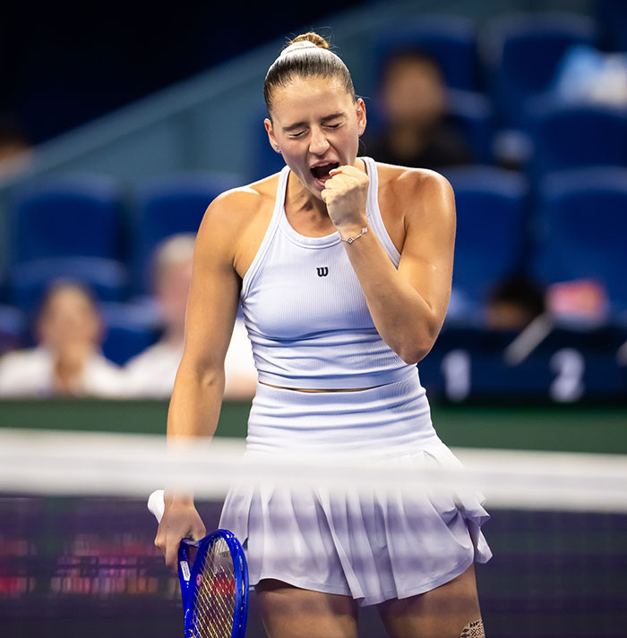 Tennis star celebrating on court during intense match, highlighting fierce rivalry and testosterone remark controversy.