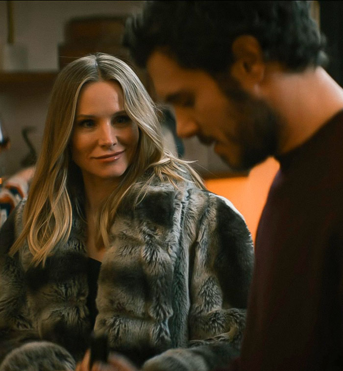 Kristen Bell wearing a fur coat, interacting with a man in a casual indoor setting amid expert backlash.