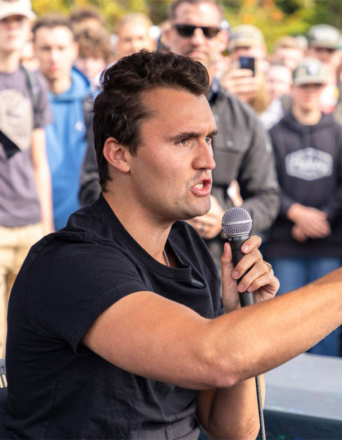 Man holding microphone speaking passionately to a crowd, related to Teacher of the Year finalist controversy and revenge.
