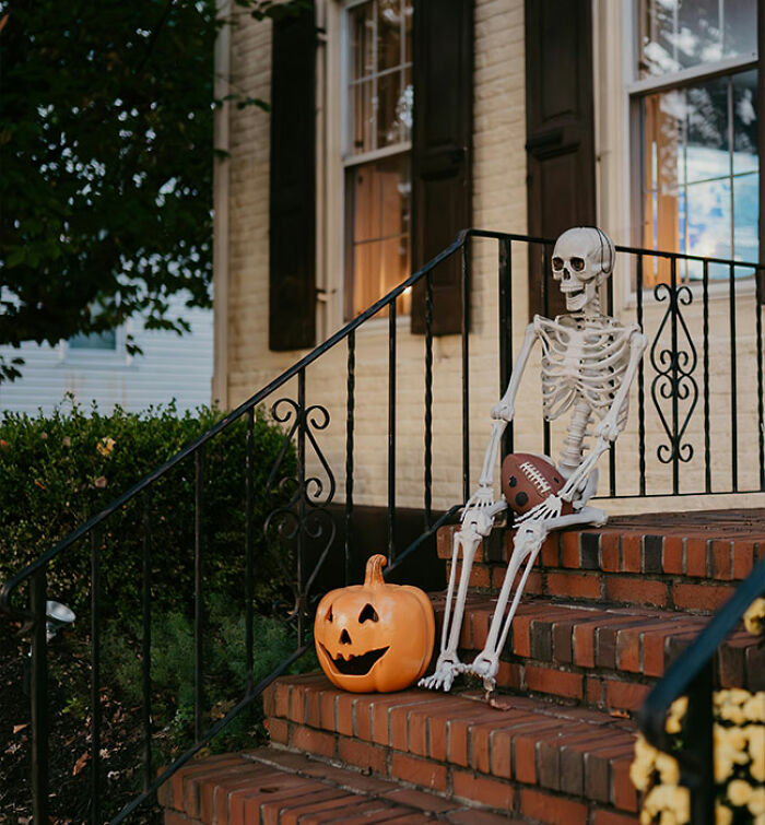 Skeleton holding football beside a carved pumpkin on porch steps, capturing Halloween and unhinged woman attack keywords.