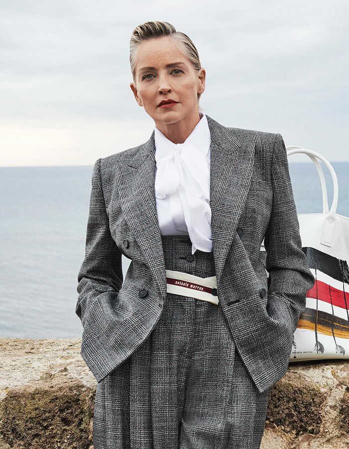 Celeb dressed in gray suit by the sea, embodying tone-deaf celeb style in mocking less wealthy people.