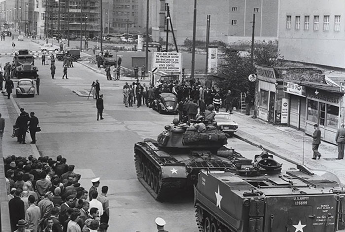 Black and white photo of military tanks and crowds on a city street, illustrating shocking history stories about rabbits and Napoleon.