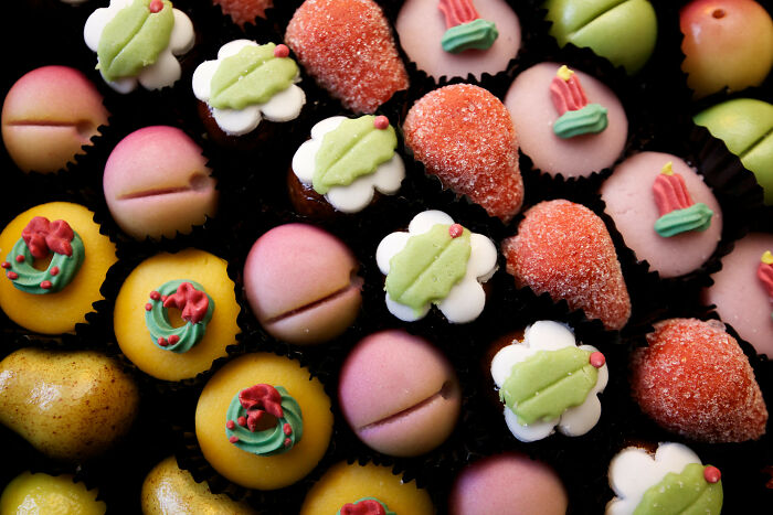Assorted colorful marzipan sweets arranged in rows, highlighting textures and details in a close-up view.