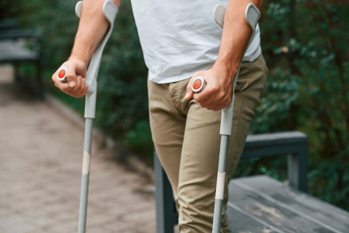 Person with disabilities using crutches outdoors, highlighting challenges faced due to rude and ableist behavior.