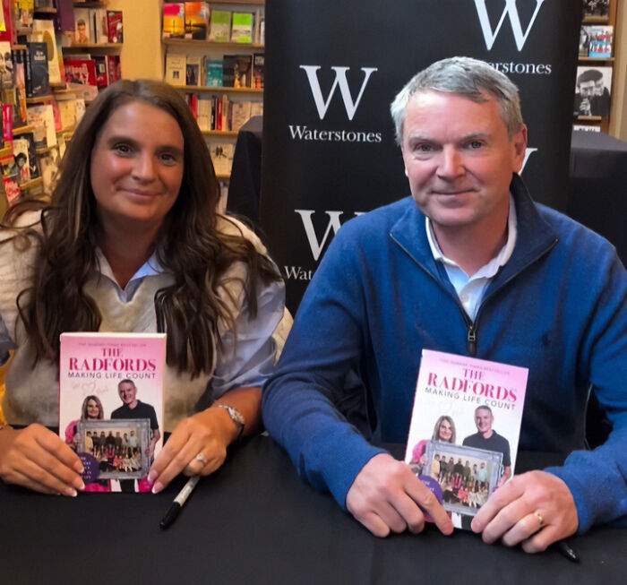 Parents of 22 holding books at a signing event, related to Disney vacation court case and fierce statement news.