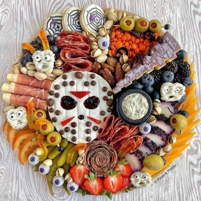 Halloween horror-themed snack platter with charcuterie, cheese, olives, and spooky edible decorations for Halloween fans.