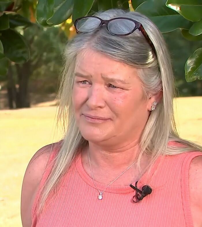 Woman with glasses on head showing emotional reaction after missing brother found alive following years locked in basement outdoors.