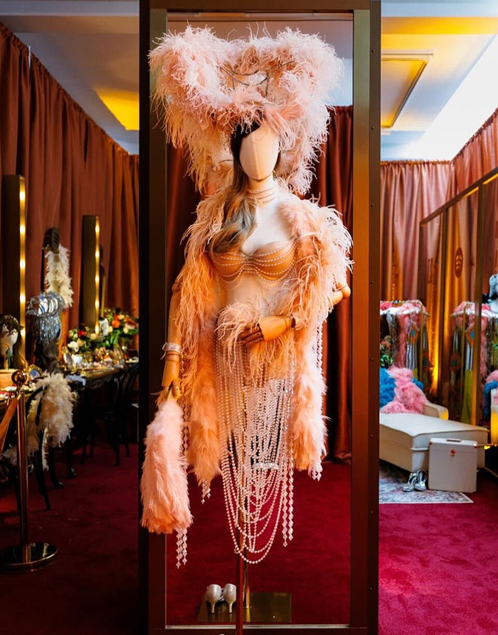 Showgirl costume with feathers and pearls displayed in a dressing room, related to Taylor Swift tone deaf backlash. Showgirl costume with feathers and pearls displayed in a dressing room, related to Taylor Swift tone deaf backlash.