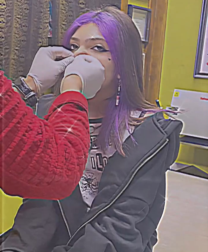 Teen girl with purple hair getting a facial piercing, highlighting controversy over letting a 16-year-old get a pelvic tattoo. Teen girl with purple hair getting a facial piercing, highlighting controversy over letting a 16-year-old get a pelvic tattoo.