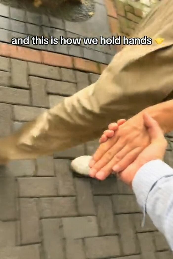 Thumbless man and another person holding hands in a creative way on a brick sidewalk, showcasing unique life hacks. Thumbless man and another person holding hands in a creative way on a brick sidewalk, showcasing unique life hacks.