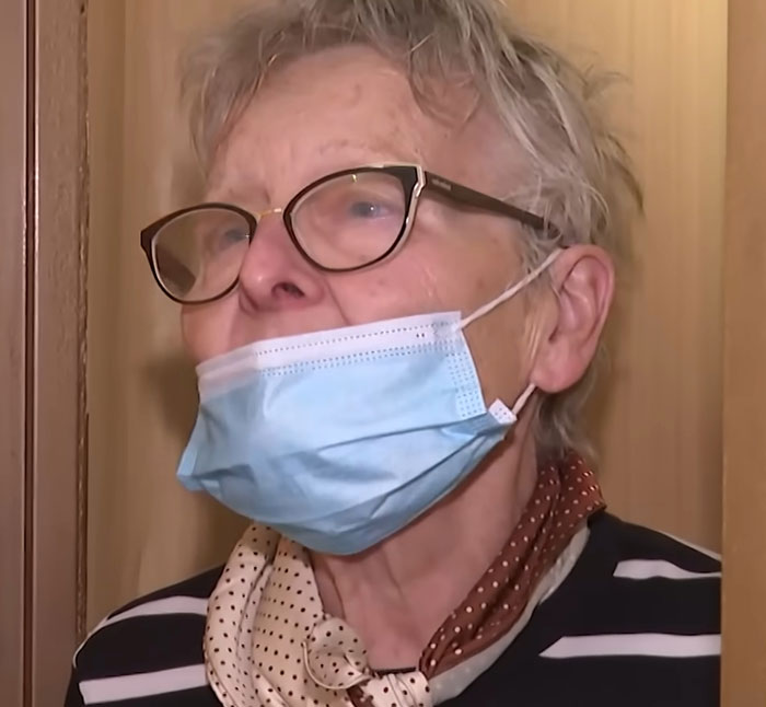 Elderly woman wearing glasses and face mask, speaking indoors about teen missing 27 years found living in parents&rsquo; house.