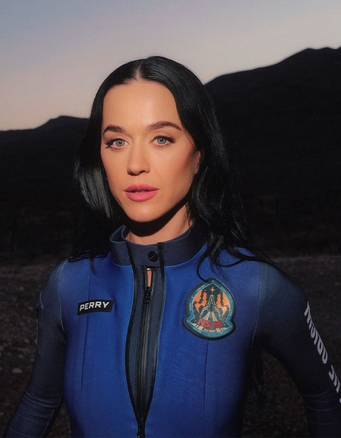Katy Perry in a blue jumpsuit posing outdoors at dusk, related to Justin Trudeau romance midlife crisis news.