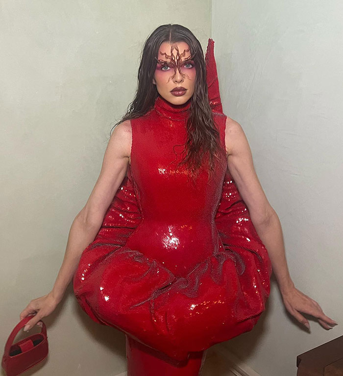 Julia Fox wearing a striking red barely-there dress with dramatic makeup at a gala event, sparking online backlash.