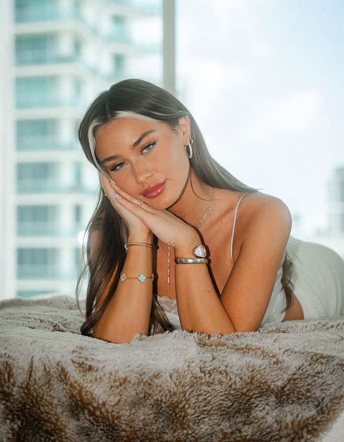 Adult star resting on a plush blanket, wearing jewelry and a white top, reflecting on wedding vows and personal challenges.
