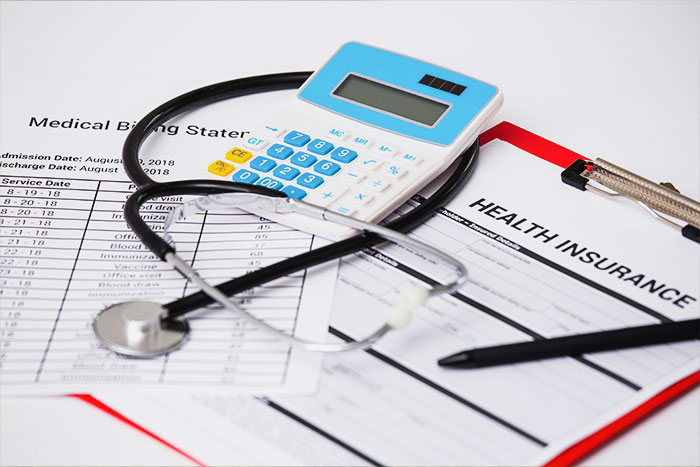 Health insurance documents with stethoscope and calculator illustrating denied coverage over key details.