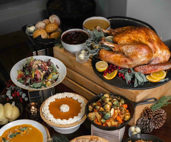 Table filled with Thanksgiving food including roasted turkey and vegetables, with people sharing worst crimes in their hometowns.