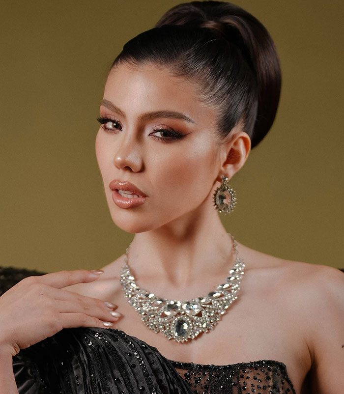 Miss Panama wearing elegant jewelry and makeup, posing gracefully in a glamorous black outfit onstage.