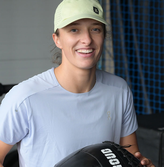 Tennis star smiling in athletic wear during training session amid testosterone remark controversy and rival's response.