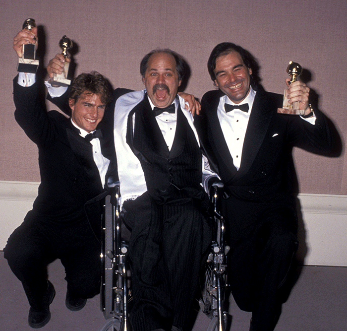 Emilio Estevez, Charlie Sheen, and another man in tuxedos holding awards and celebrating together at an event Emilio Estevez, Charlie Sheen, and another man in tuxedos holding awards and celebrating together at an event