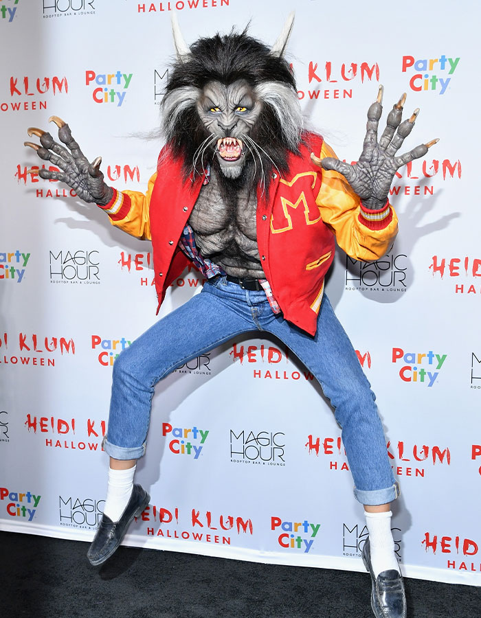 Heidi Klum in a detailed werewolf costume with a red varsity jacket and jeans at a Halloween event.