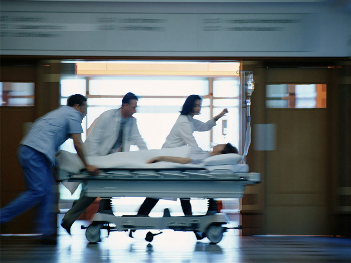 Medical team rushing patient on a stretcher in hospital corridor related to doctor arguing against wife&rsquo;s autopsy case.