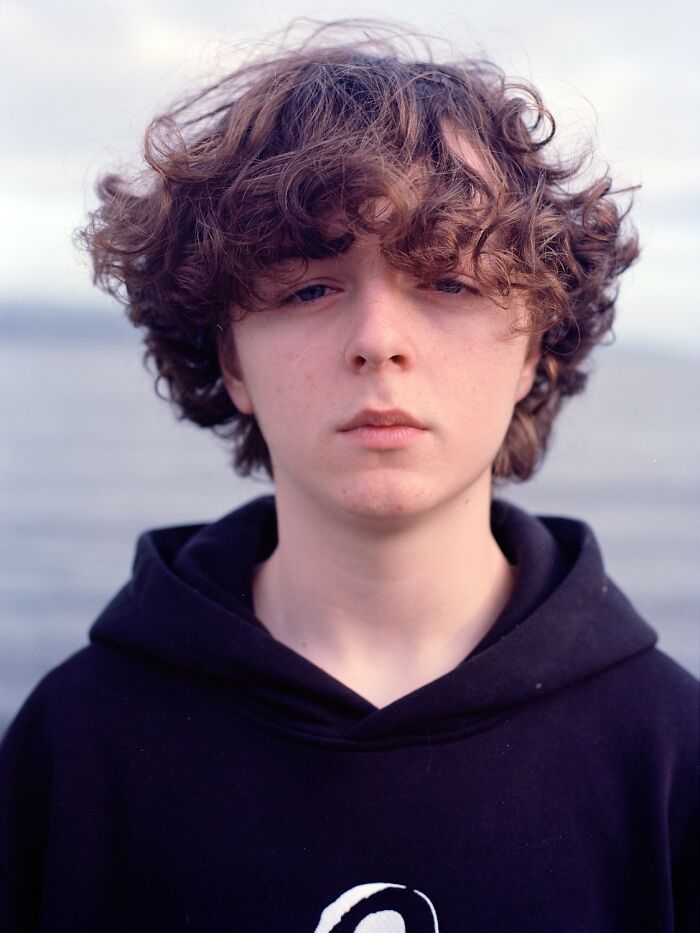 Young woman with freckles wearing a red and beige jacket, featured in award-winning photos from the 2025 Photographer of the Year contest