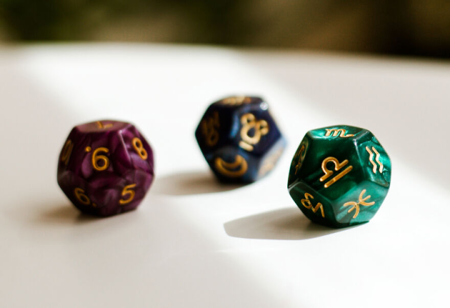 Three colorful 12-sided dice with gold numbers and symbols, representing the 999 angel number concept.