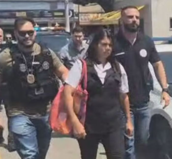 Woman in custody escorted by police officers during arrest related to alleged serial criminal and chilling confession case.