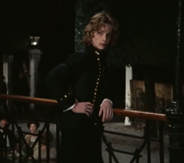 Young actor known as the most beautiful boy in the world posing outdoors in a vintage military-style jacket at night.