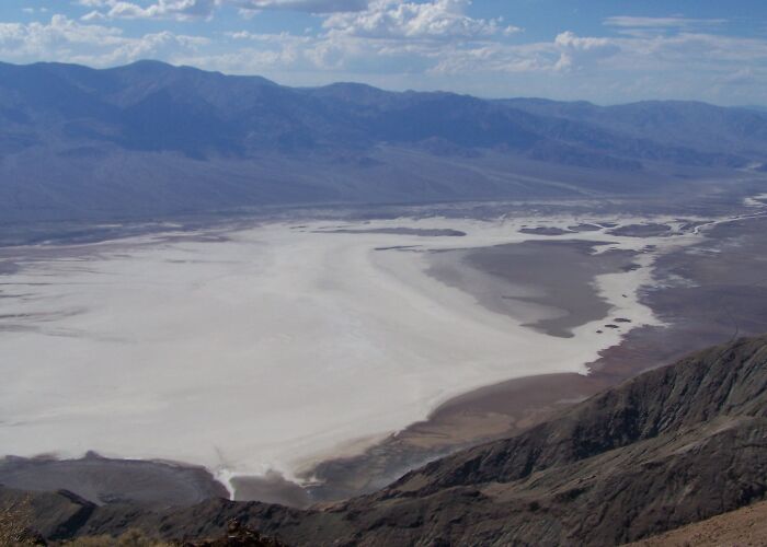 A vast salt flat in a desert valley with mountains in the background showing extreme weather records on Earth.